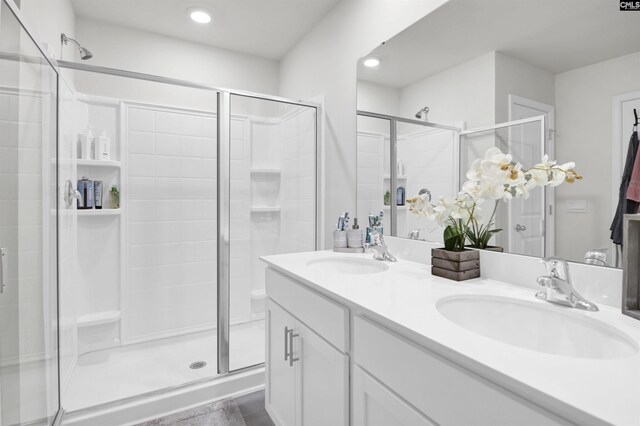 full bath with a shower stall, recessed lighting, double vanity, and a sink