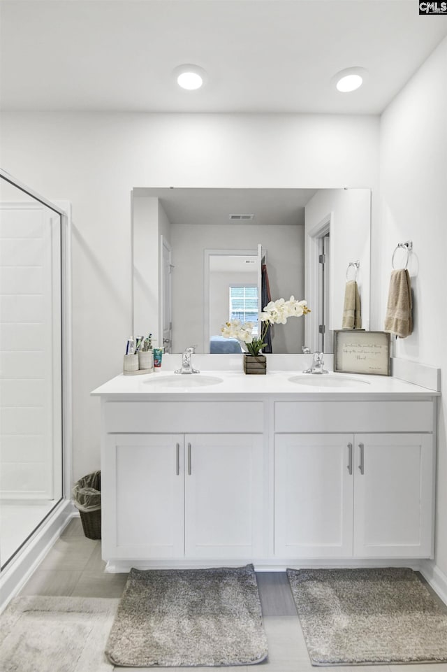 full bath with a shower stall, double vanity, a sink, and visible vents