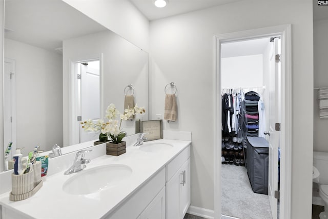 bathroom with a sink, a spacious closet, toilet, and double vanity