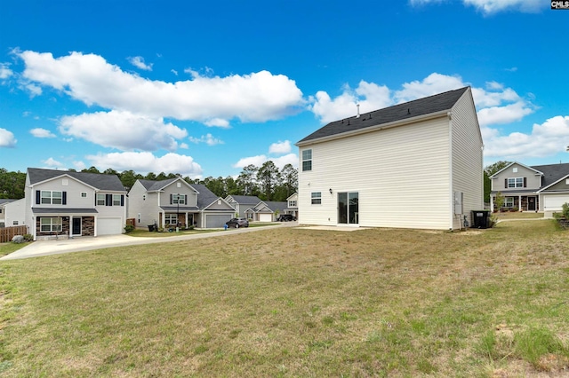 rear view of house with cooling unit, a garage, a residential view, and a lawn