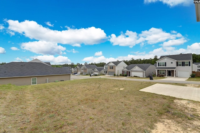 view of yard featuring an attached garage, a residential view, and concrete driveway