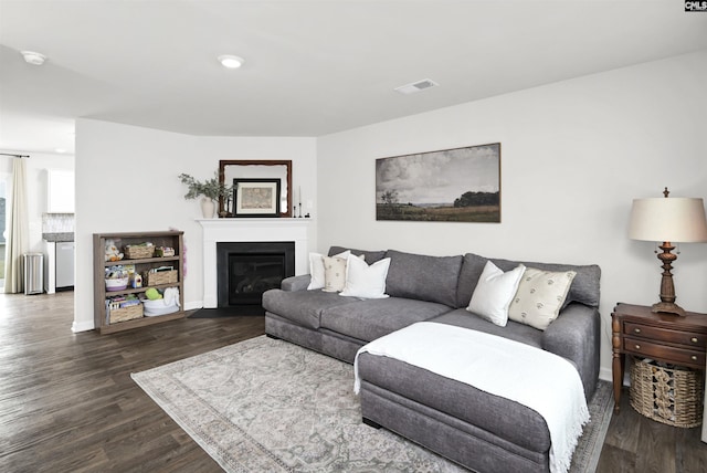 living area with a glass covered fireplace, dark wood-style flooring, baseboards, recessed lighting, and visible vents