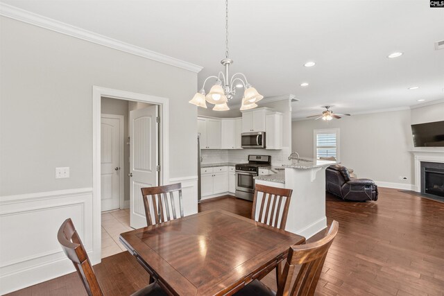 126 Sunset Bay Ln, Lexington, SC 29072 - dining area with ornamental molding, recessed lighting, a wainscoted wall, a fireplace with flush hearth, and ceiling fan with notable chandelier