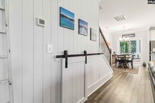 hallway featuring visible vents, ornamental molding, a chandelier, stairway, and wood finished floors