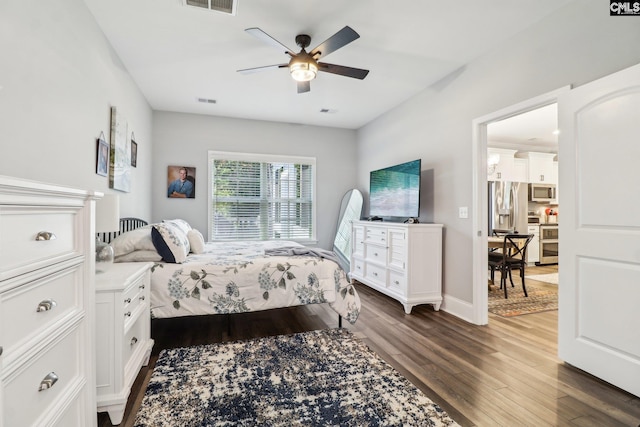 bedroom featuring a ceiling fan, dark wood-style floors, visible vents, and stainless steel refrigerator with ice dispenser