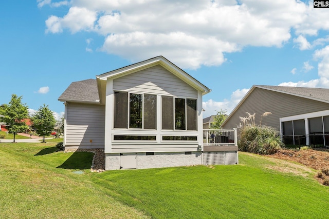 rear view of house featuring crawl space, a shingled roof, a sunroom, and a yard