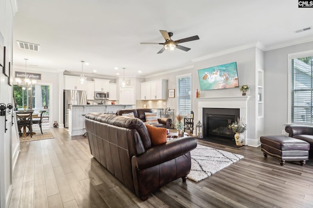 living room with wood finished floors, ceiling fan with notable chandelier, and visible vents