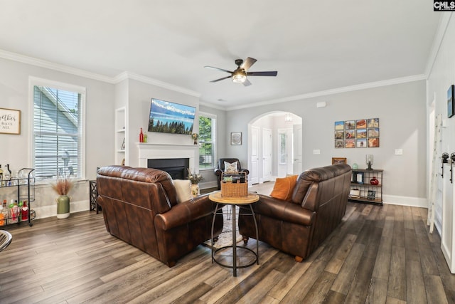 living area with arched walkways, a fireplace, a ceiling fan, and dark wood finished floors