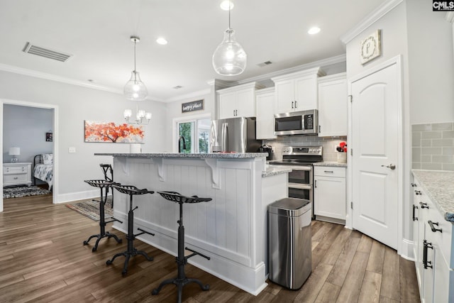 kitchen featuring a center island, white cabinetry, visible vents, a kitchen bar, and appliances with stainless steel finishes