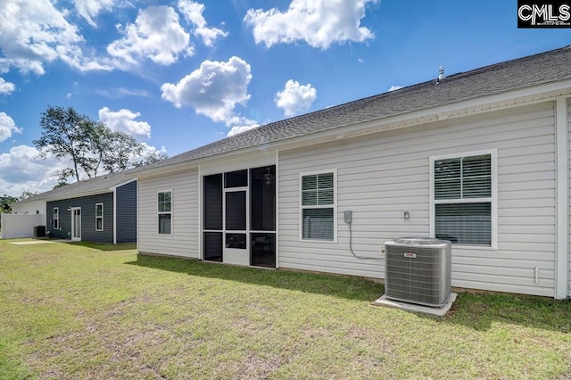 rear view of house featuring cooling unit, a sunroom, and a lawn