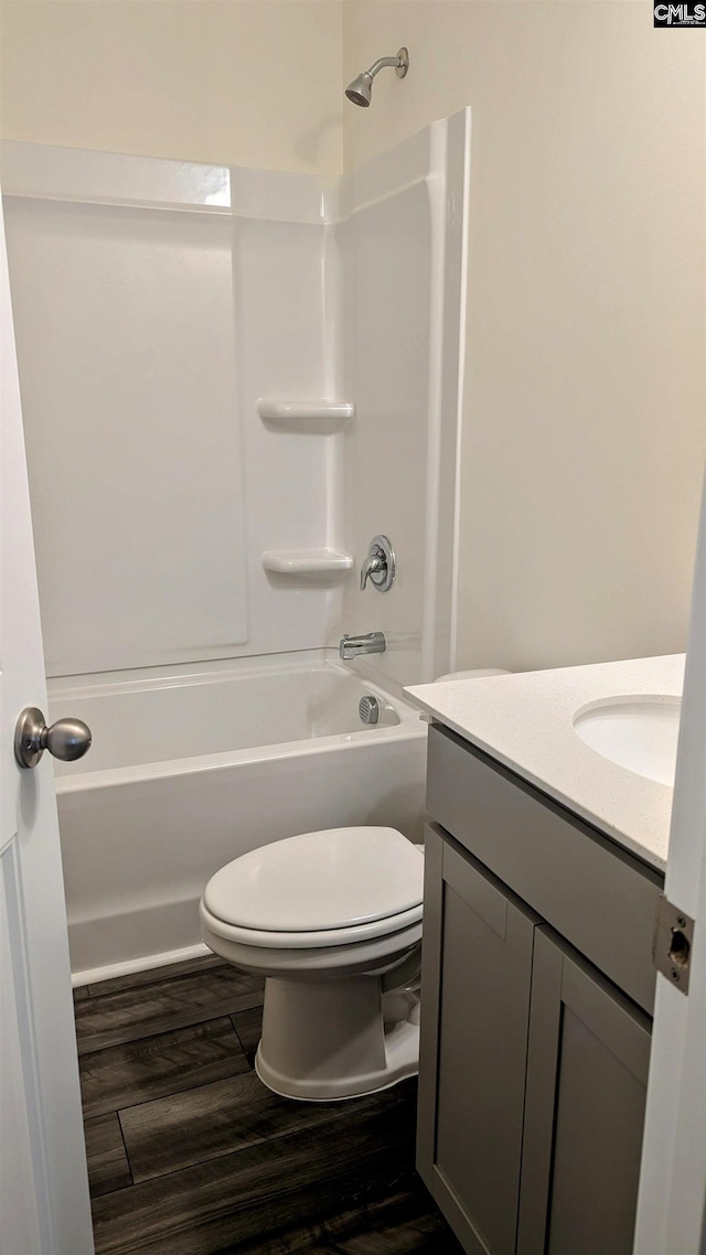bathroom with toilet, wood finished floors, vanity, and bathing tub / shower combination