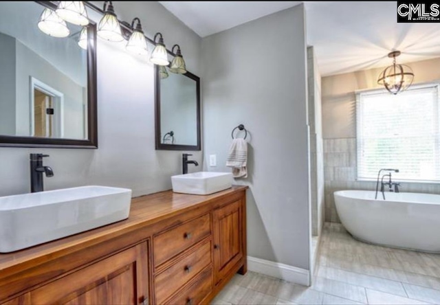 full bathroom with a soaking tub, a sink, a notable chandelier, and double vanity