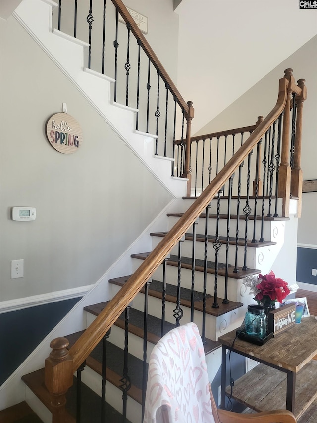 stairway featuring a high ceiling and baseboards