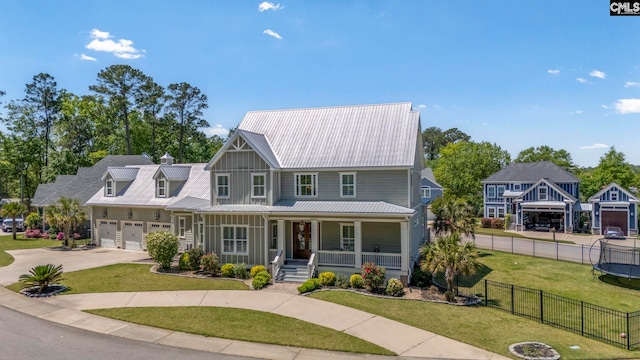 view of front facade with a front lawn, driveway, a porch, metal roof, and fence