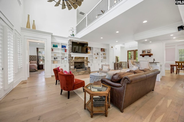 living room with light wood-type flooring, recessed lighting, a notable chandelier, crown molding, and a fireplace