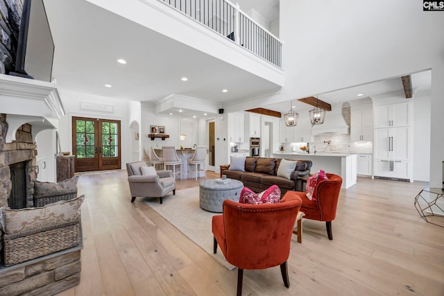 living area featuring recessed lighting, ornamental molding, a stone fireplace, and light wood-type flooring