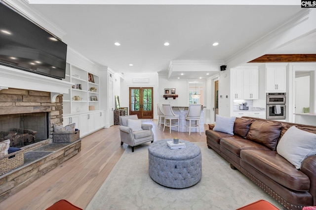 living room featuring recessed lighting, a stone fireplace, ornamental molding, and light wood-style flooring