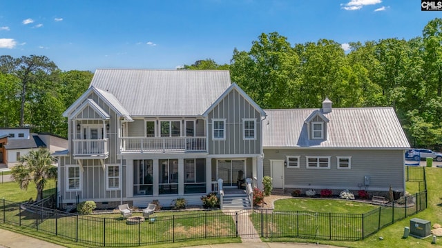 rear view of house with a fenced front yard, metal roof, a balcony, a yard, and crawl space
