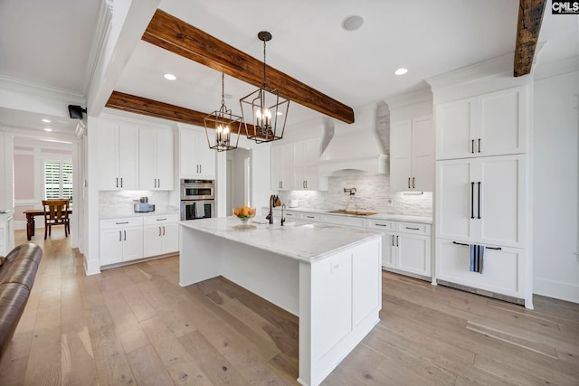 kitchen featuring backsplash, a sink, premium range hood, light wood-style floors, and black electric stovetop