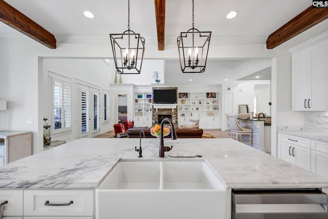kitchen featuring an island with sink, a sink, beamed ceiling, open floor plan, and a notable chandelier