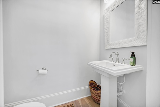 half bathroom featuring baseboards and wood finished floors