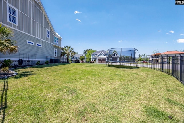 view of yard with a residential view, a trampoline, and fence