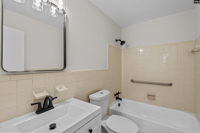 full bathroom with toilet, vanity, shower / tub combination, and tile walls