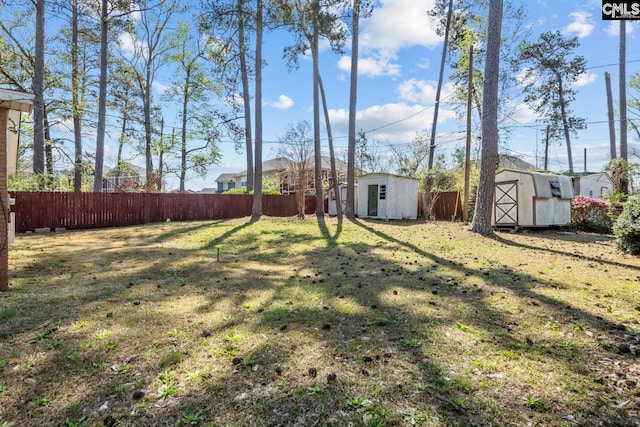 view of yard featuring an outdoor structure, fence, and a storage shed