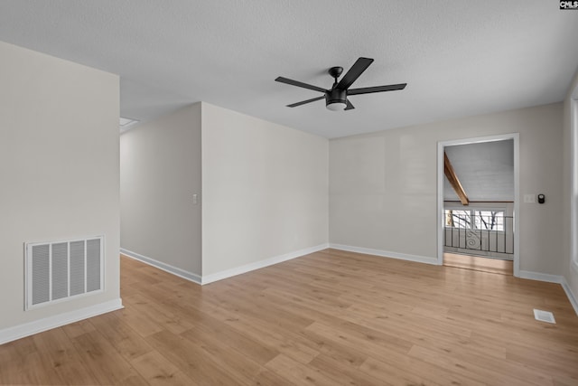 spare room with a ceiling fan, a textured ceiling, visible vents, and light wood-style flooring