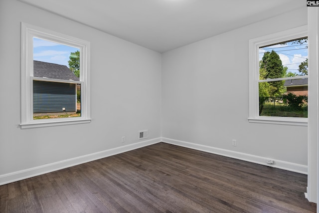 unfurnished room featuring visible vents, baseboards, and dark wood-style flooring
