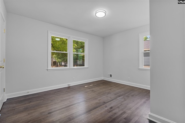 spare room featuring baseboards, visible vents, and dark wood-style flooring