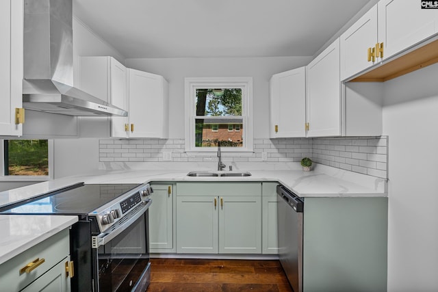 kitchen featuring tasteful backsplash, a sink, stainless steel appliances, wall chimney exhaust hood, and light stone countertops