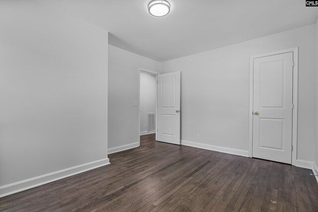 unfurnished bedroom featuring visible vents, baseboards, and dark wood-style flooring