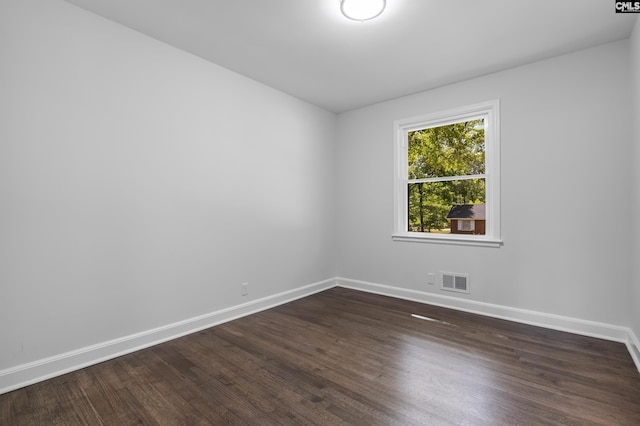 unfurnished room with baseboards, dark wood-type flooring, and visible vents