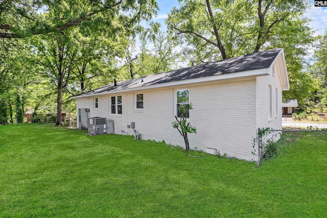 back of property with fence, brick siding, a yard, and central AC unit