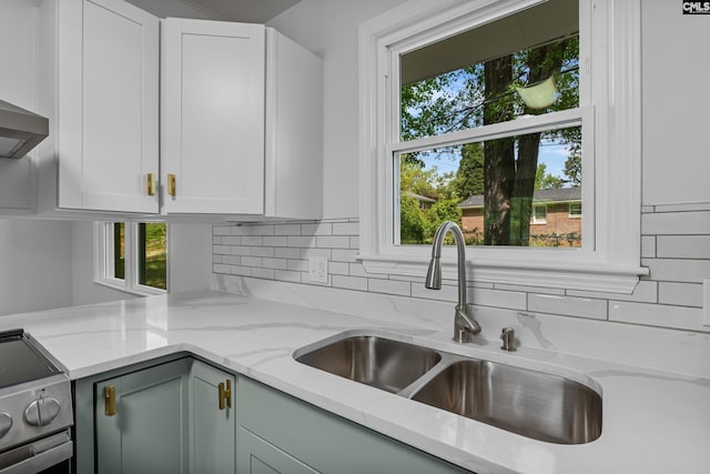 kitchen with stainless steel electric stove, plenty of natural light, decorative backsplash, and a sink