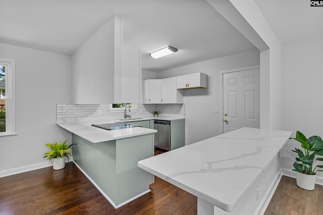 kitchen with a peninsula, dishwasher, a sink, and light stone counters
