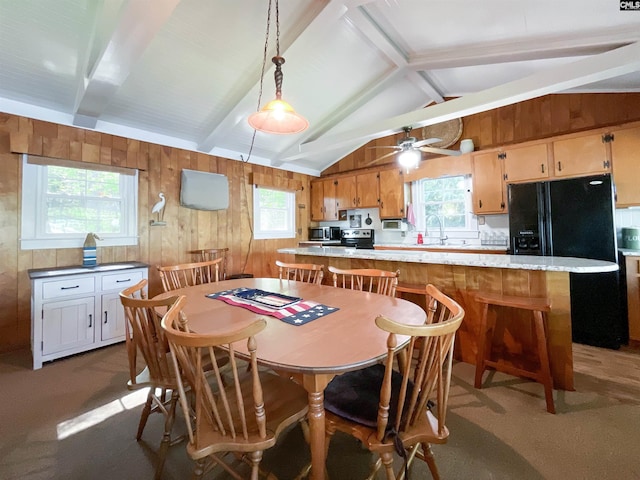 dining space featuring vaulted ceiling with beams, wood walls, a ceiling fan, and dark colored carpet