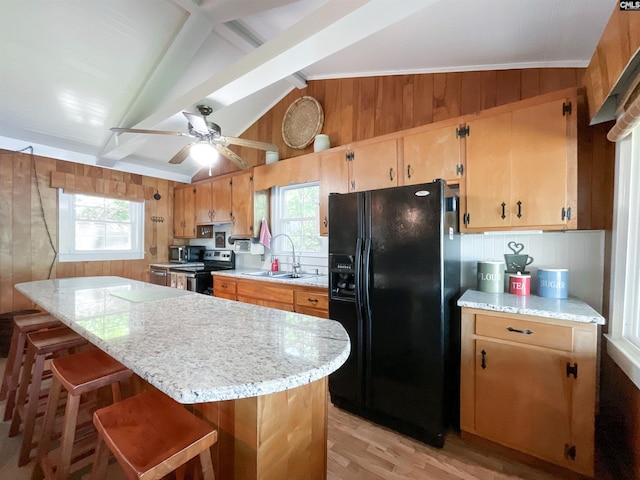 kitchen featuring wood walls, electric stove, a sink, a wealth of natural light, and black fridge with ice dispenser