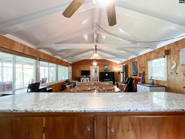 kitchen featuring brown cabinetry, lofted ceiling with beams, and wood walls
