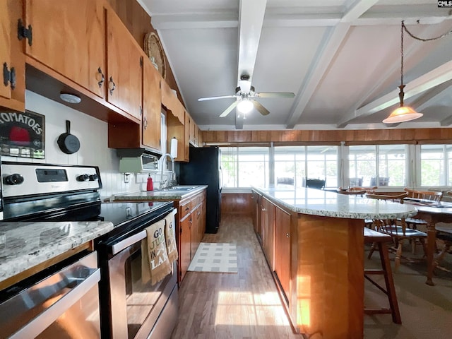 kitchen with a sink, brown cabinetry, light wood-style floors, ceiling fan, and appliances with stainless steel finishes