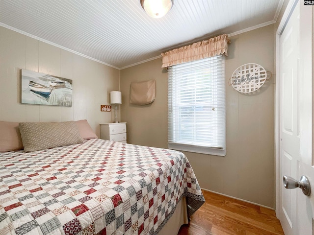 bedroom featuring baseboards, wood finished floors, a closet, and crown molding