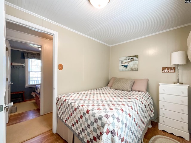 bedroom with wood finished floors and ornamental molding