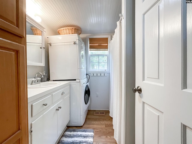 washroom featuring a sink, visible vents, light wood-style floors, stacked washer and clothes dryer, and laundry area