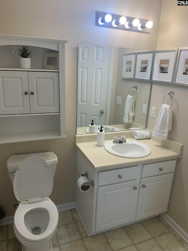half bathroom with vanity, toilet, and baseboards