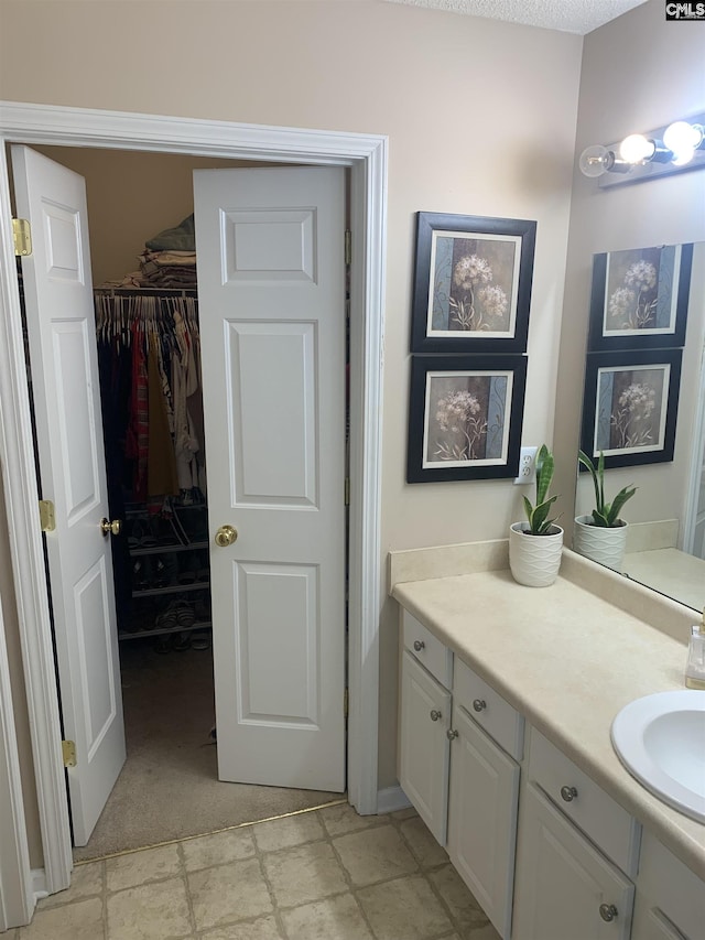 bathroom with vanity, a spacious closet, and stone finish flooring