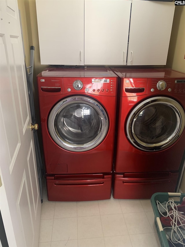 laundry area featuring cabinet space, tile patterned flooring, and washer and clothes dryer