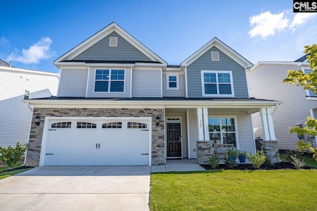 craftsman-style house featuring concrete driveway, stone siding, covered porch, a front yard, and a garage