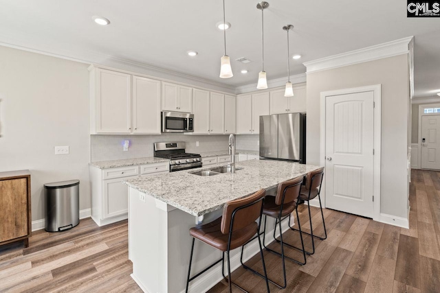 kitchen with stainless steel appliances, a kitchen breakfast bar, a sink, white cabinetry, and ornamental molding