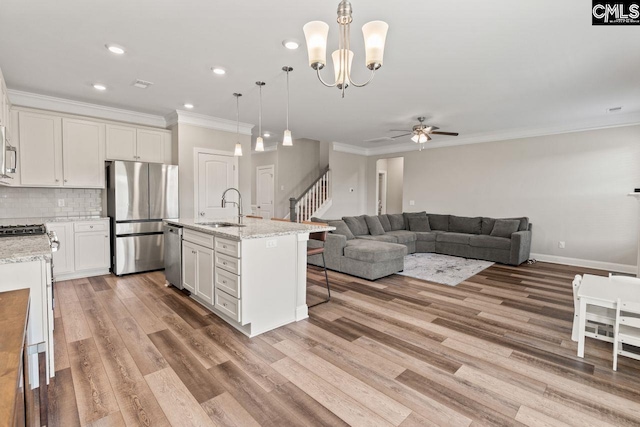 kitchen with ceiling fan with notable chandelier, appliances with stainless steel finishes, ornamental molding, and a sink